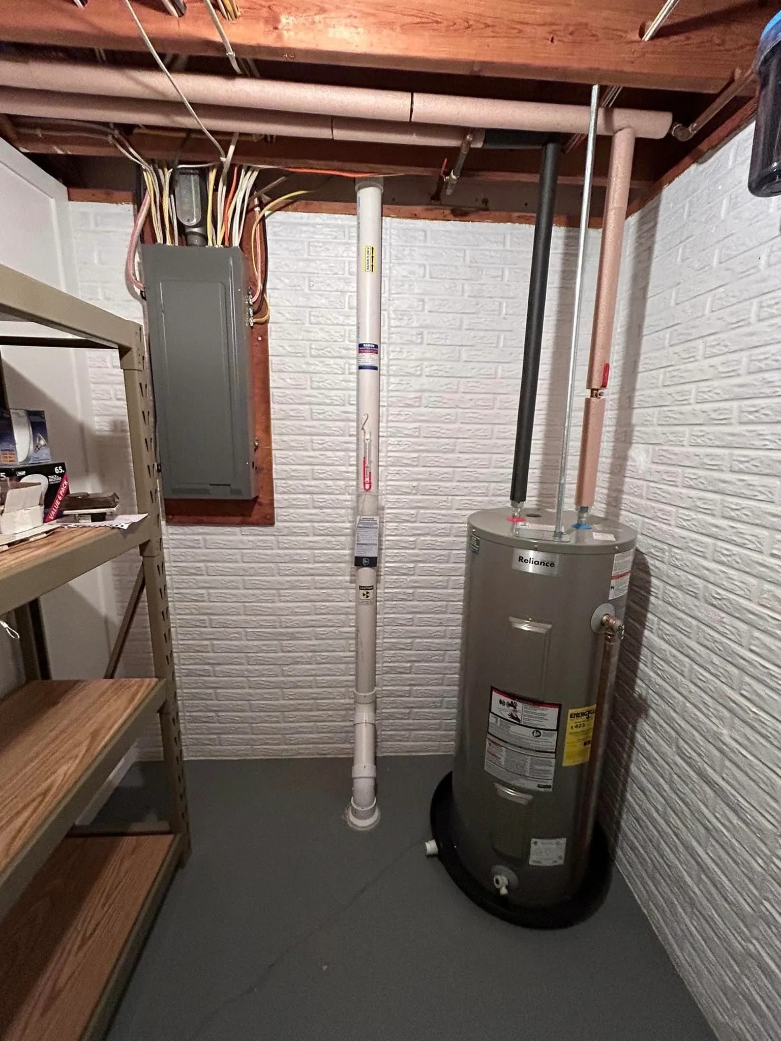 White radon pipe against a painted basement wall